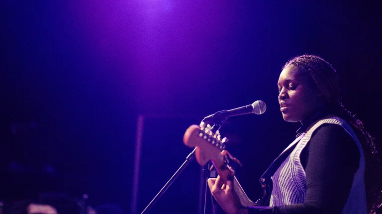 Woman playing guitar while singing on a stage