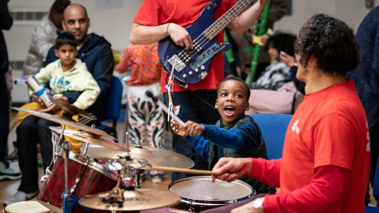 Child playing drums with teacher 