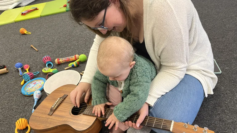 Adult and baby playing a guitar