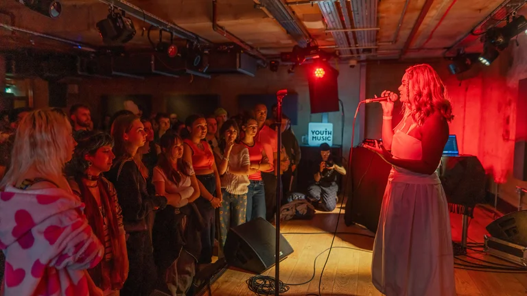 pritt sings on stage under red lighting to a crowd