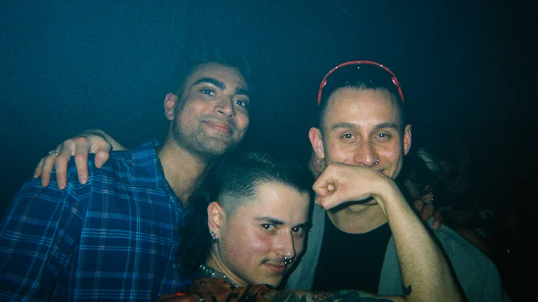 three people pose for a photo in a nightclub