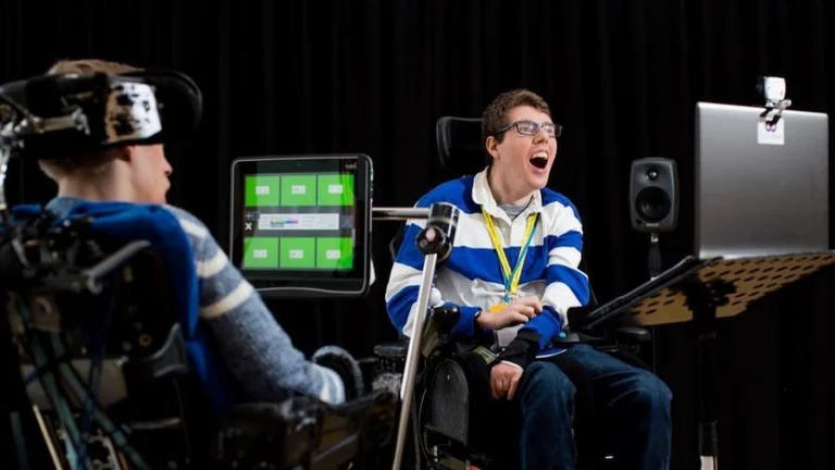 Two participants, both wheelchair users, laugh together 