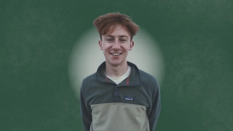 This is a photograph of the person interviewed for this article. They are standing looking directly at the camera smiling. The background is green with a white circle behind the person.  