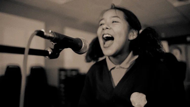 young girl singing into a microphone and smiling, black and white