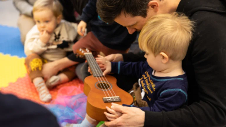 Babies holding a ukulele 