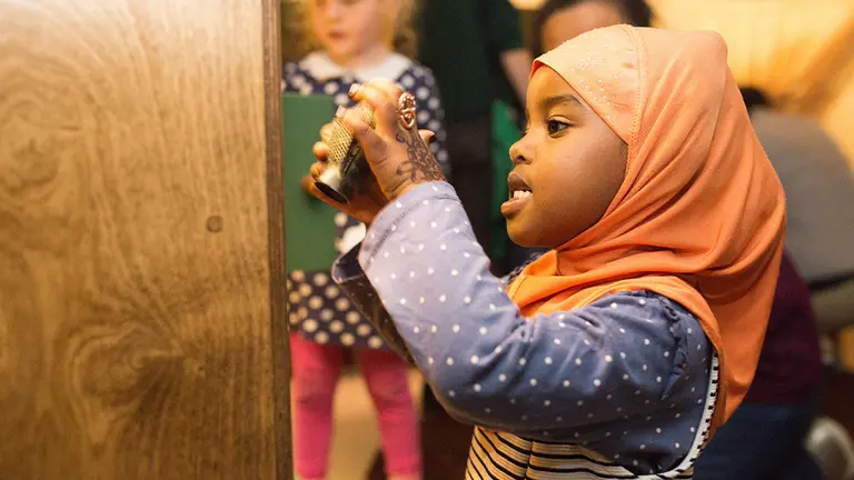 A child wearing a hijab plays with an object