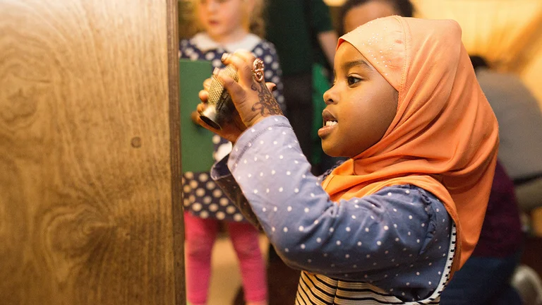 A child wearing a hijab plays with an object