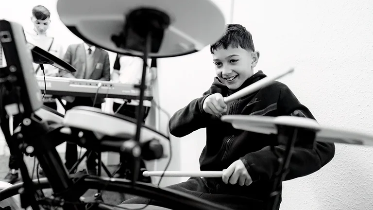 a boy plays the drums enthusiastically