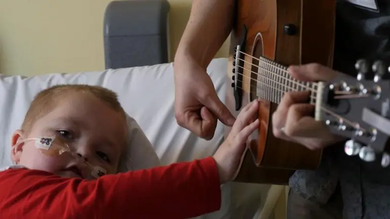 patient on bed strumming guitar with nick