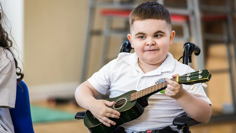 A wheelchair-user young child playing ukelele