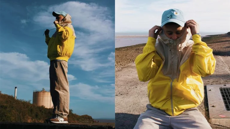 Luke RV posing on a beach wearing a bright yellow jacket and blue hat