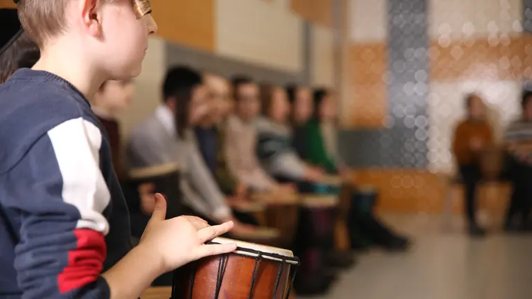 Young children playing small drums in a semi circle