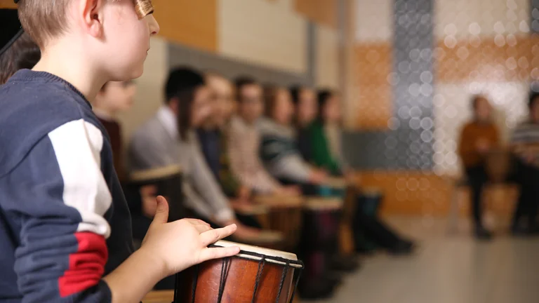 Young children playing small drums in a semi circle