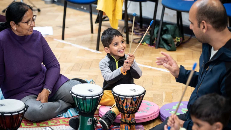 Child smiling and holding drum sticks