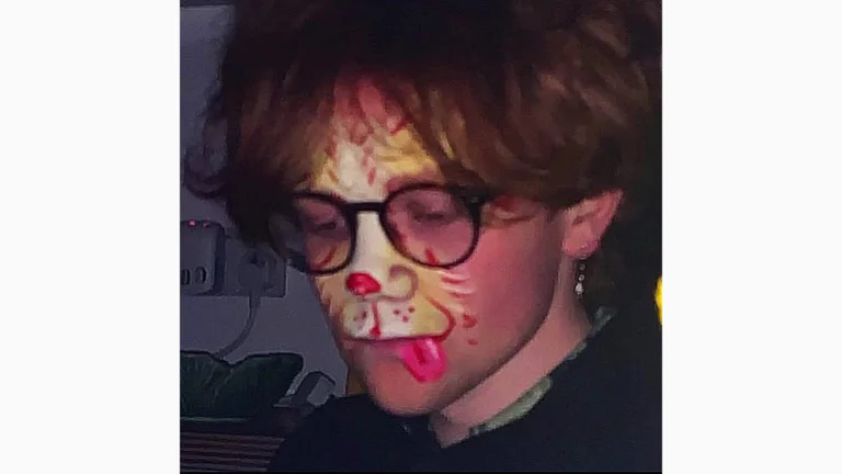 a person with auburn hair and glasses wears animal face paint