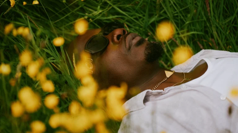 ebeneezer lies down in grass, surrounded by yellow flowers