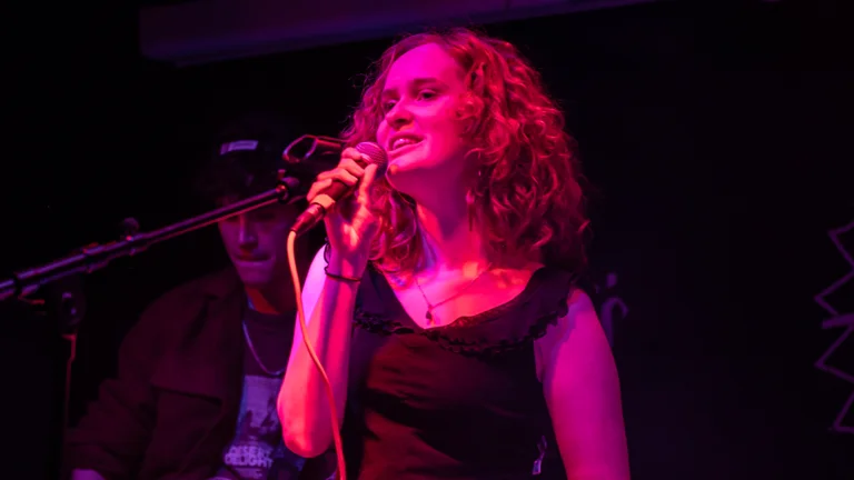 erin has curly fair hair and holds a mic on stage