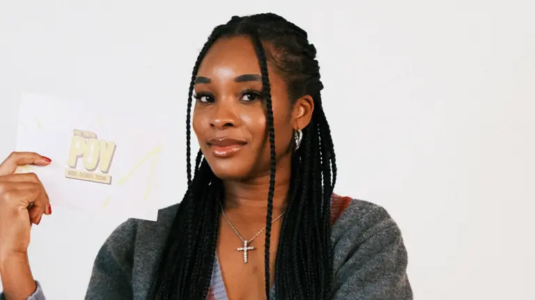 maya egbo wears her hair in braids and holds a card with 'brits POV' written on the front