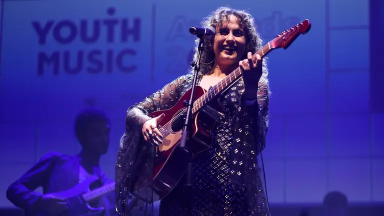 image of peri rae performing on stage, playing the guitar and smiling