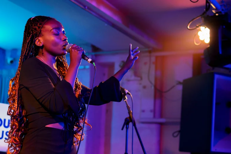 a woman with long braids sings into a mic