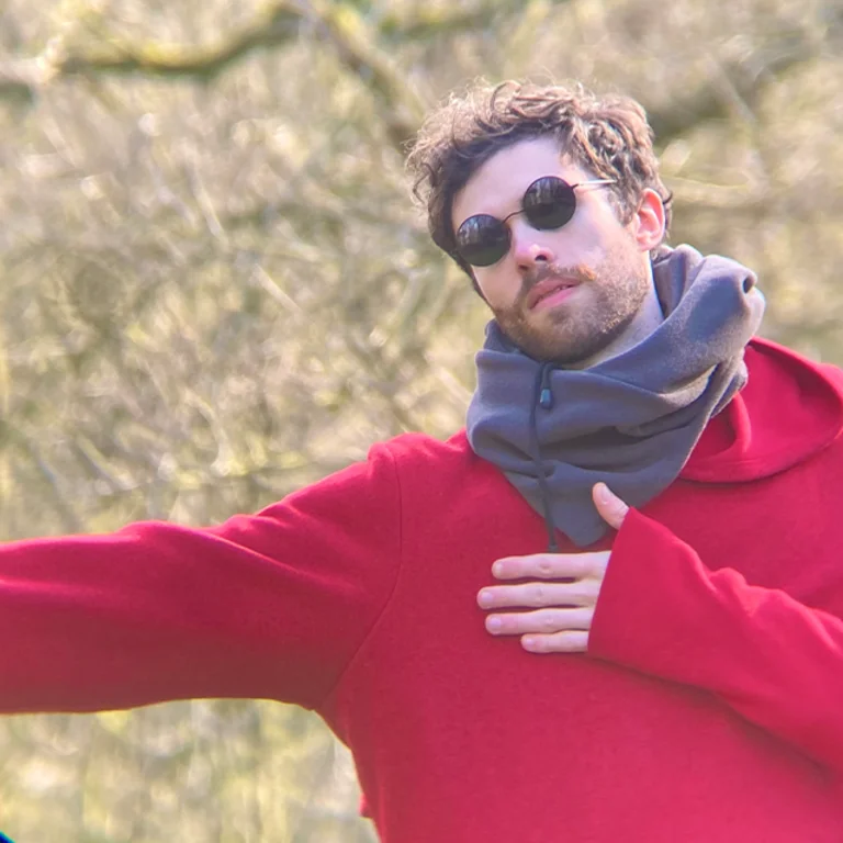 Alex in a red sweater, grey scarf and black sunglasses