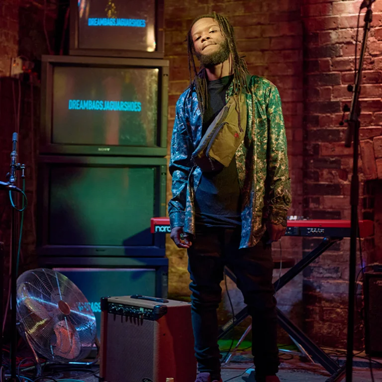 a man with dreadlocks stands next to an amp on a stage