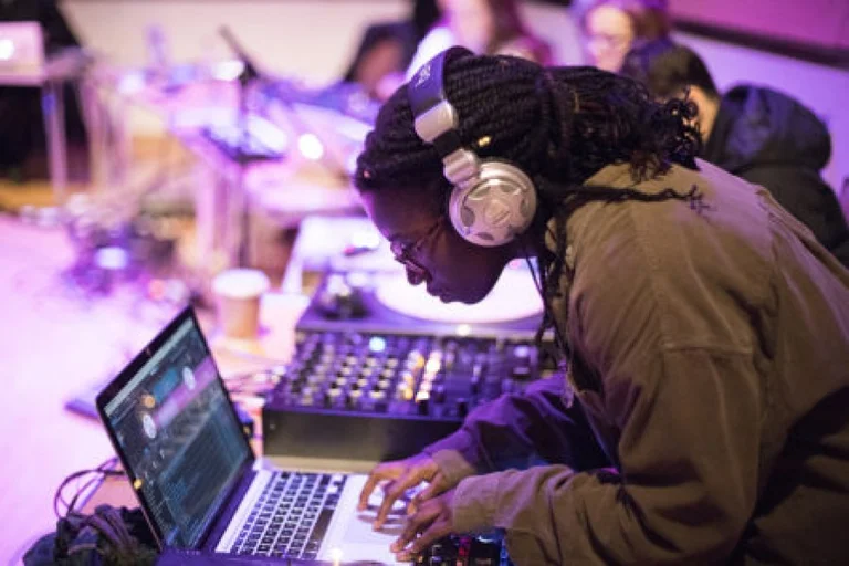 woman wearing headphones producing music on a laptop