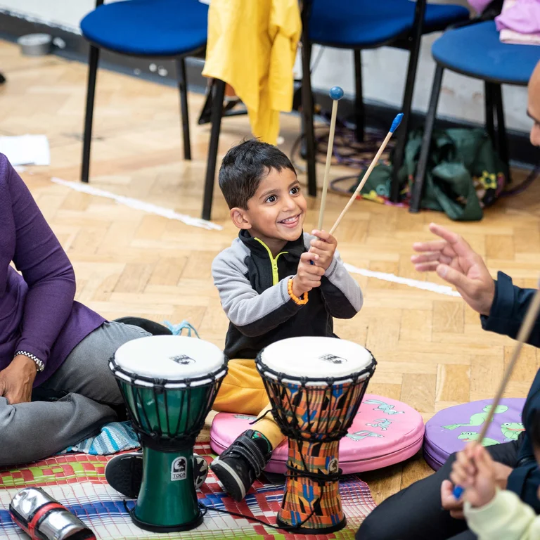 Child smiling and holding drum sticks