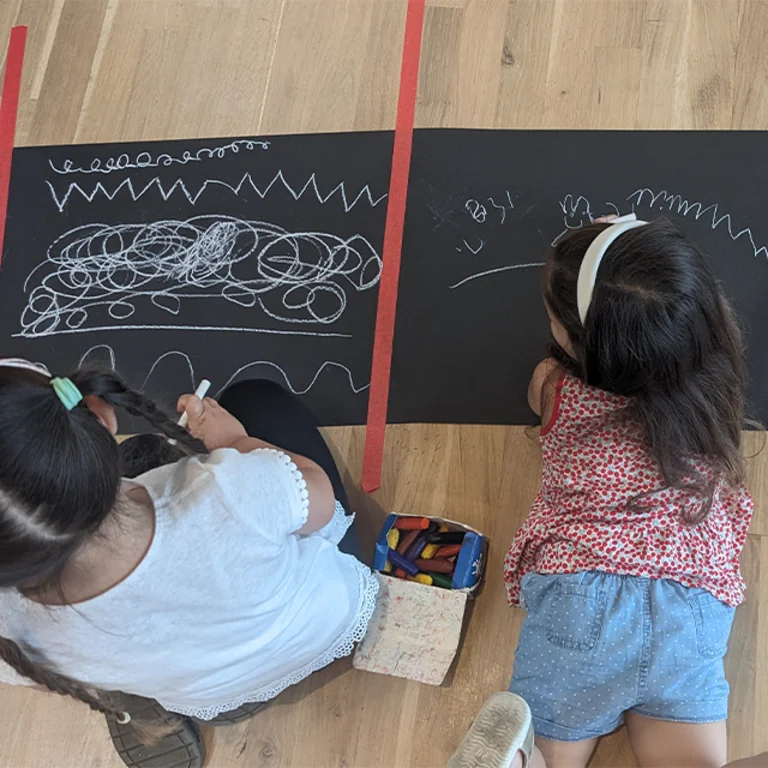 two children drawing on a black board lying on the ground